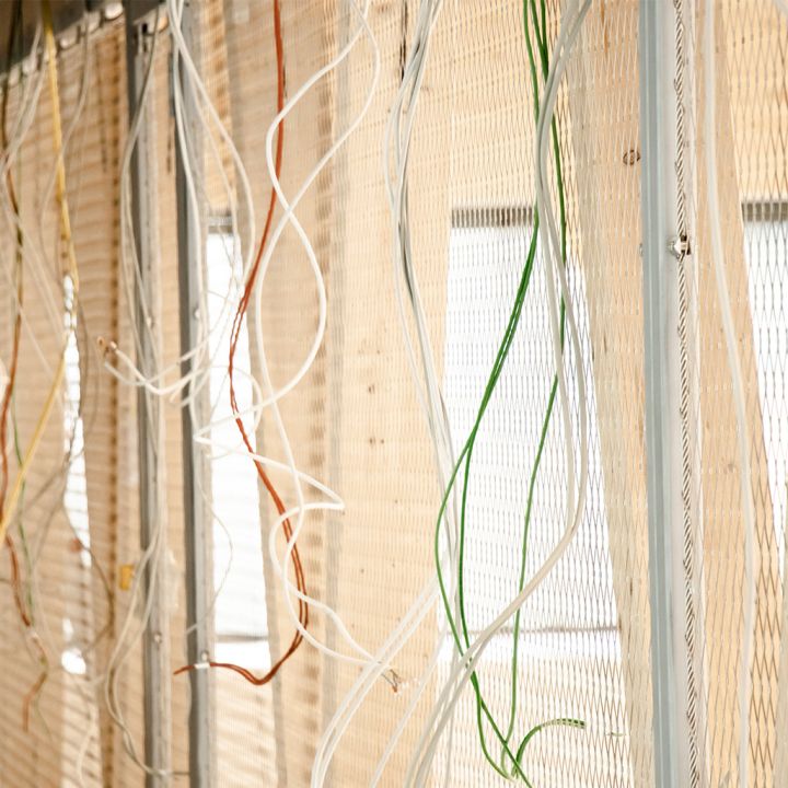 Bunte elektrische Leitungen hängen lose in einer Wandinstallation.