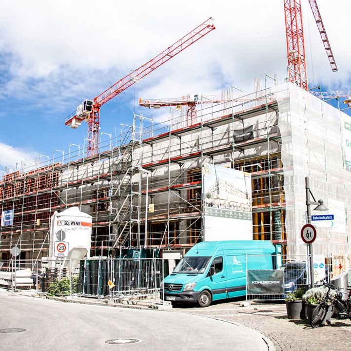 Baustelle mit Fassadengerüst und roten Kränen an einem Neubauprojek.