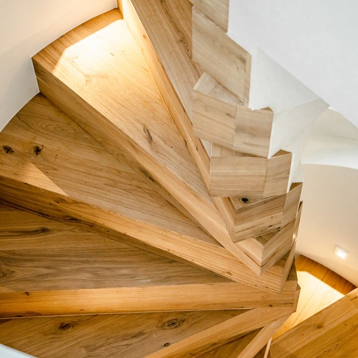 Eine weitere Ansicht einer modern beleuchteten Holz-Wendeltreppe.