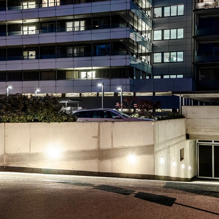 Ein modernes Wohngebäude mit beleuchteter Einfahrt bei Nacht.