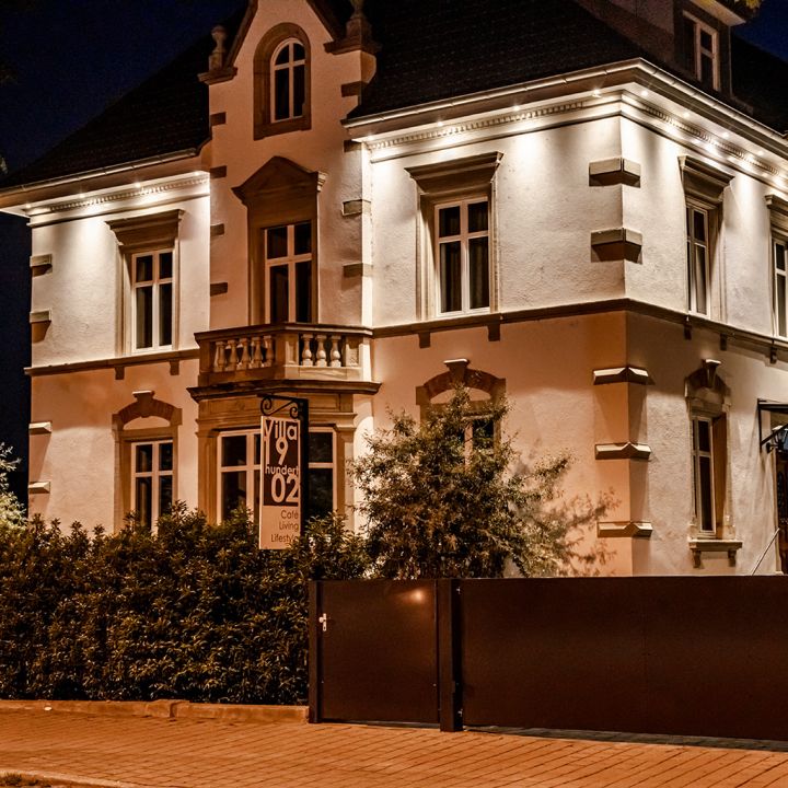 Ein Jugendstilgebäude ist abends durch Außenbeleuchtung stimmungsvoll in Szene gesetzt.