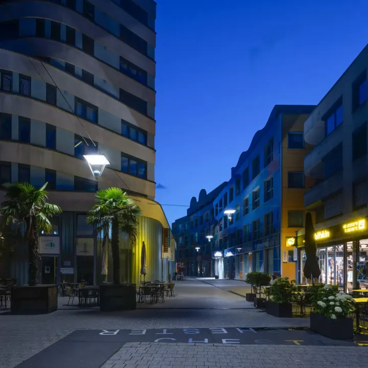 Blick auf eine weitere abendliche Einkaufsstraße mit beleuchteten Läden.