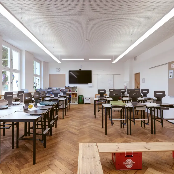 Ein heller Klassenraum mit moderner Beleuchtung und vielen Fenstern.