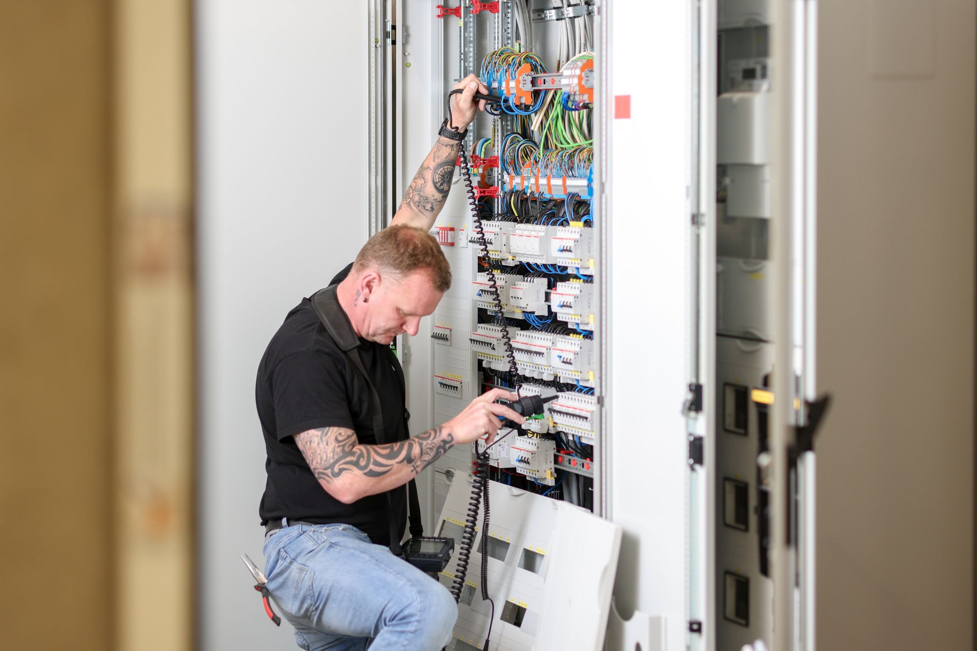 Ein Techniker prüft oder installiert die Elektronik in einem großen Schaltschrank.