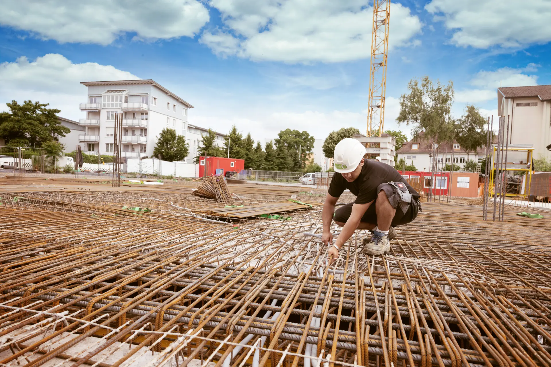 Ein Bauarbeiter verlegt Kabel auf einer großen Baustelle mit Bewehrungsstahl.